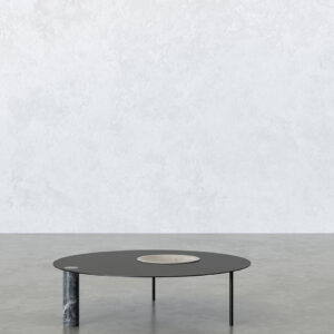 Full view of the Satellite low table: round black steel top with an off-centre light marble bowl insert, supported by thin black metal legs and a grey-veined marble cylinder leg.